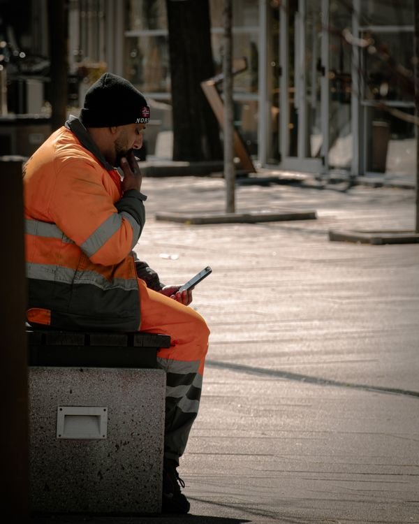 City worker in reflective clothing checking a smartphone, illustrating geofenced time tracking on a job site