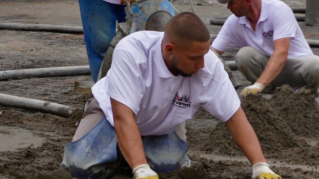 Construction workers leveling wet concrete for a smooth finish on a building site