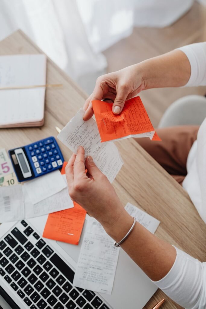 Hands holding a receipt over notes and a calculator on a desk