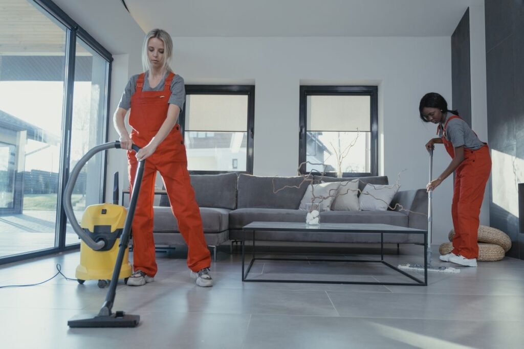 Two cleaners vacuuming and sweeping a modern living room