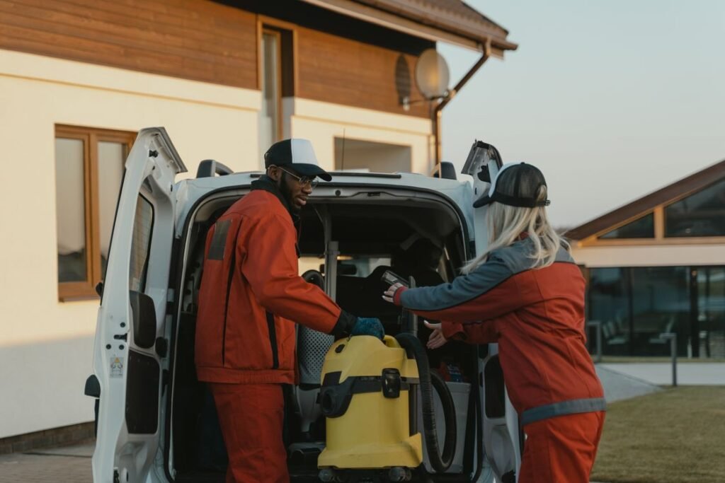Two cleaners loading equipment into a service van