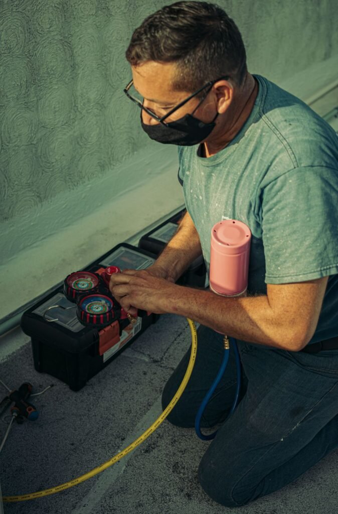 HVAC technician kneeling outdoors performing maintenance work with tools