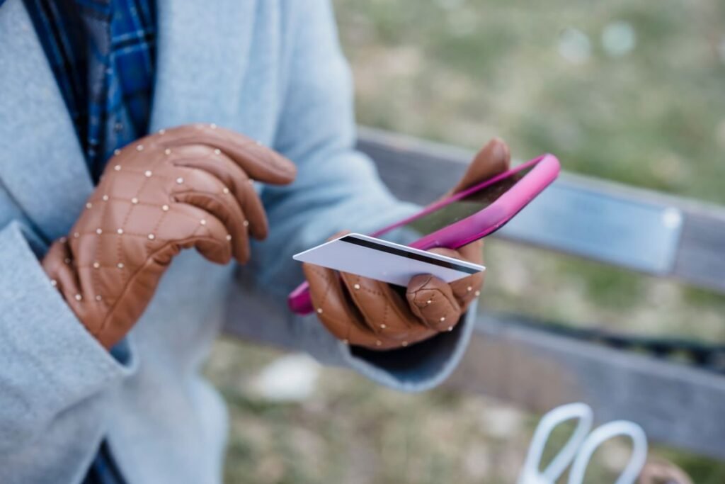 Close-up of hands holding a smartphone and credit card making a mobile payment outdoors