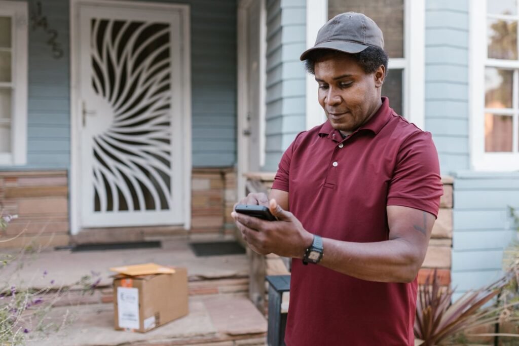 Delivery worker checking a phone at a residential door