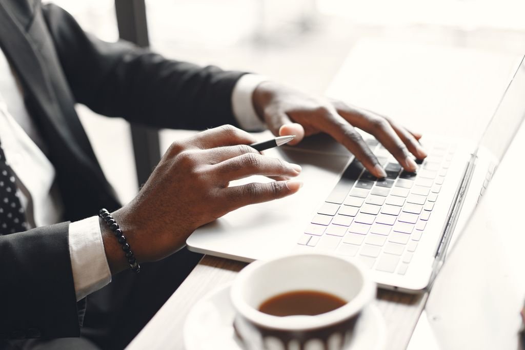 Close-up of a man using a laptop while holding a pen