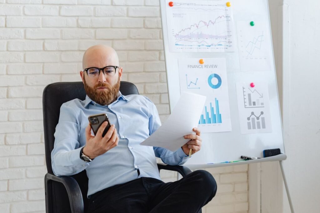 Business owner reviewing paperwork alongside data on a smartphone