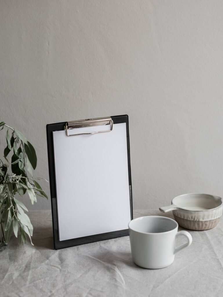 Blank paper on a clipboard beside a coffee mug on a textured desk