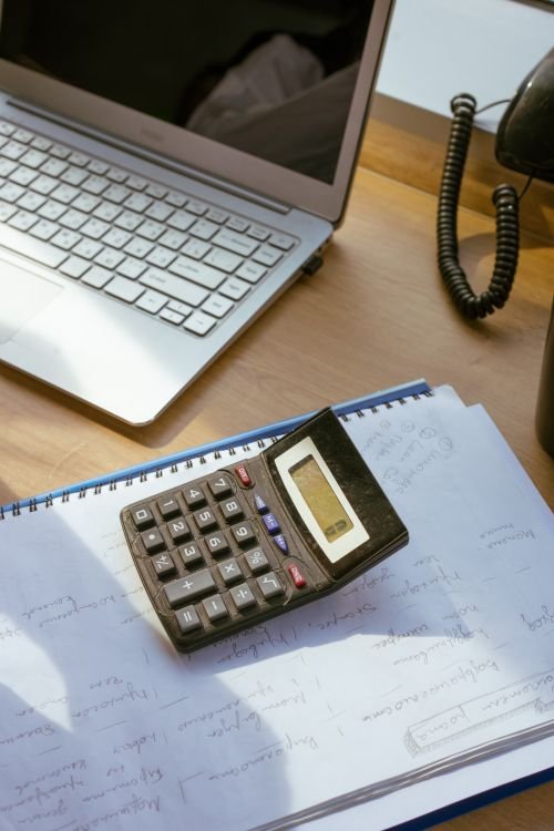 Calculator, laptop, and notes on a wooden desk