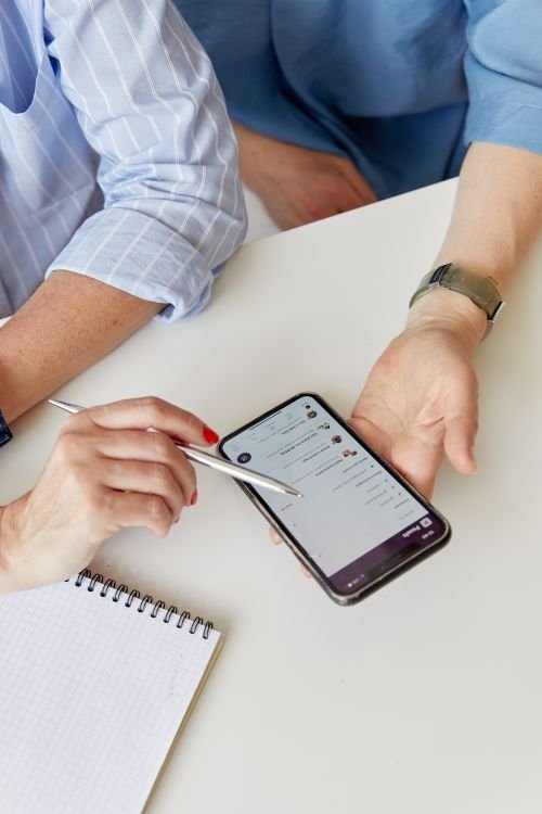 Two people collaborating over a smartphone and notepad