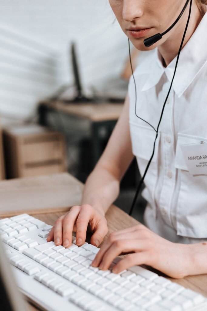 Call centre agent typing at a keyboard while wearing a headset