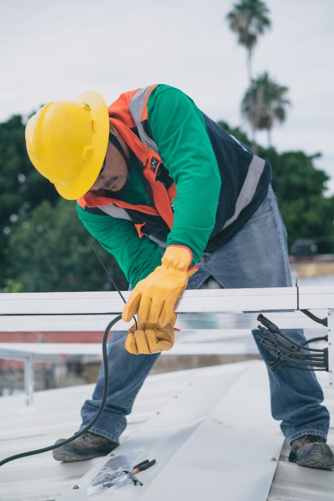 Construction worker in PPE installing electrical equipment on a roof while on a job, when missed-call options for small trade crews matter