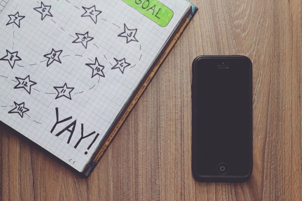 Notebook with a hand-drawn star beside a phone on a wooden desk