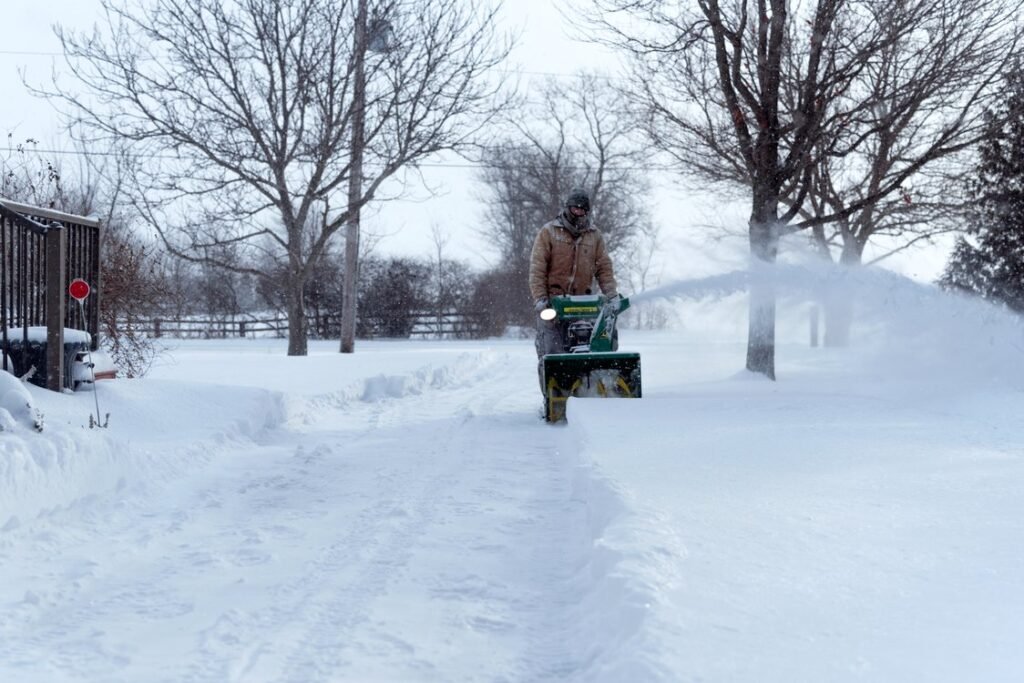 Contractor operating a walk-behind snowblower on a snow-covered driveway